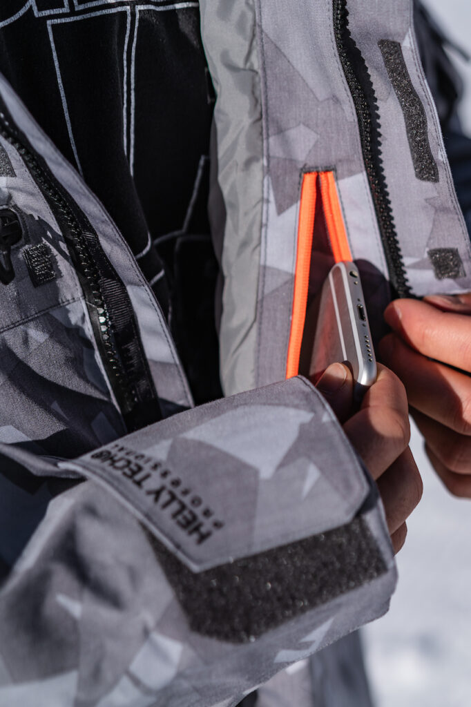 Ein Mann verstaut sein Handy in der Skijacke - Chris Gollhofer - Sportfotograf - Zürich