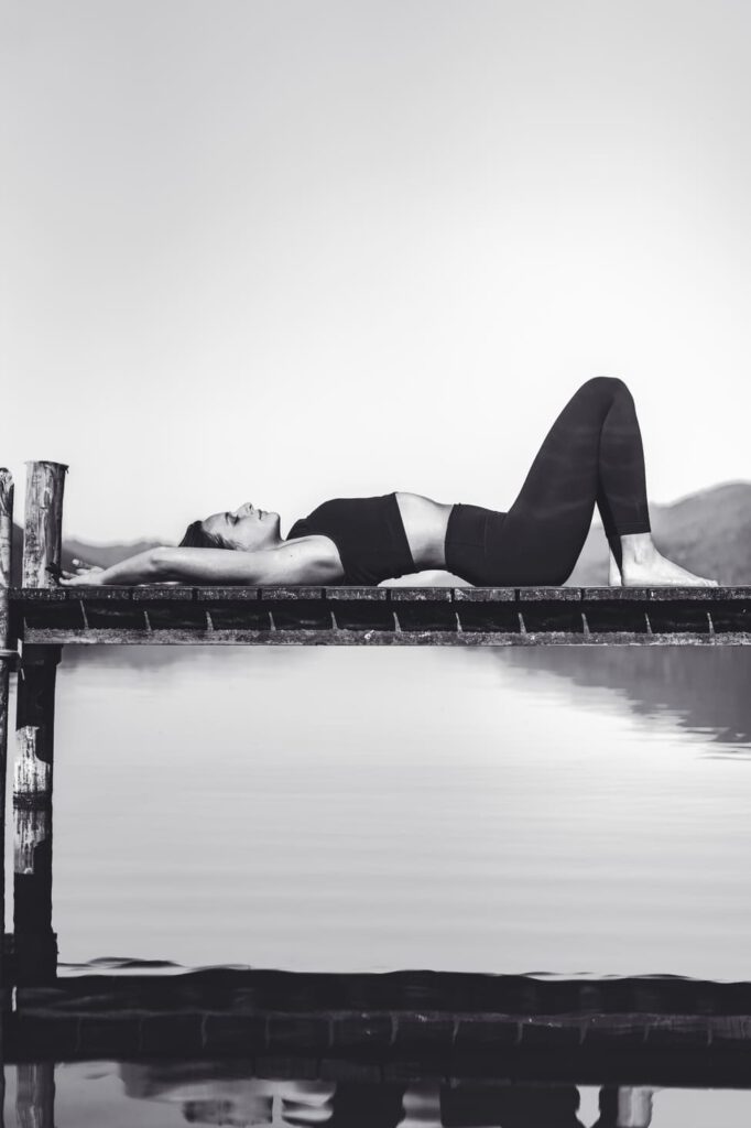 Eine Frau liegt auf einem Steg während einer Yoga Stunde - Chris Gollhfoere Lifestyle Fotografie