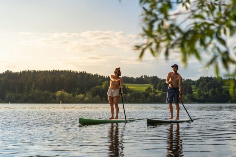 Ein Mann und eine Frau auf einem See beim stand up paddeln