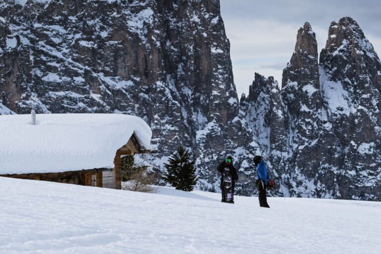 Zwei Snowboarder vor einer eingeschneiten Berghütte - People Photography Chris Gollhofer Fotograf