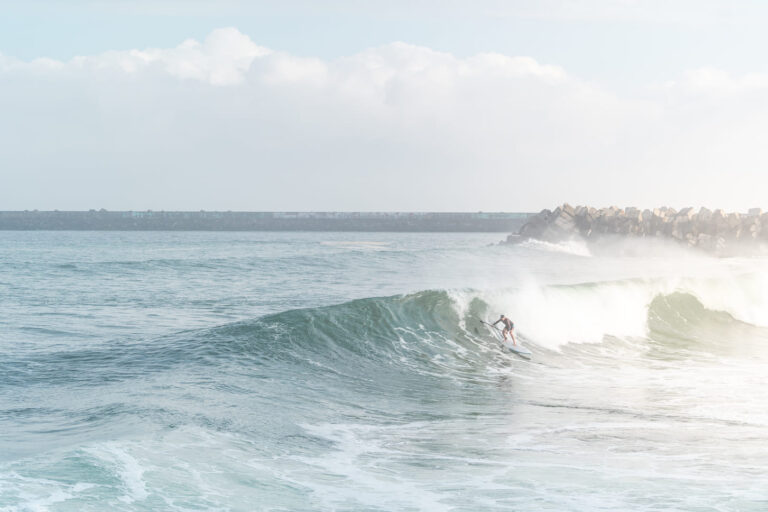 Ein Surfer surft auf einem SUP eine große Welle im Meer - Chris Gollhofer Sport Fotografie Frankreich