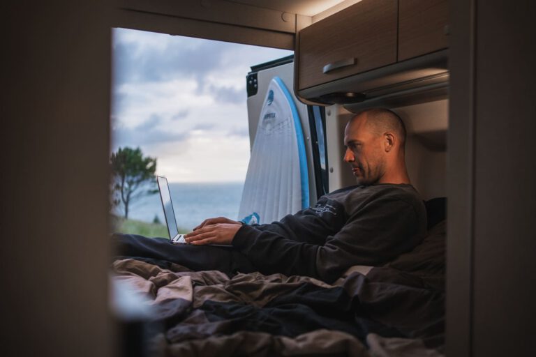 Ein Mann liegt mit dem Laptop auf dem Bett eines Wohnmobils - Chris Gollhofer Lifestyle Fotografie Frankreich