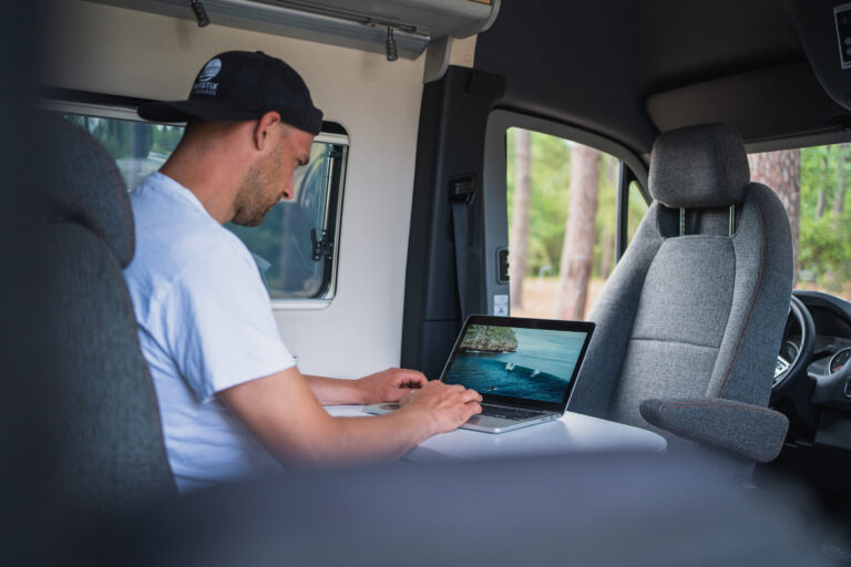 Ein Mann arbeitet in einem Wohnmobil an seinem Laptop - Chris Gollhofer Lifestyle Fotografie